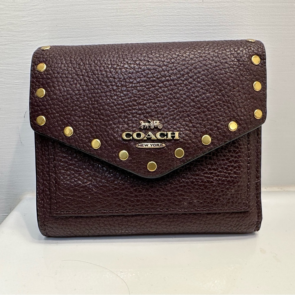 Compact Studded Leather Coach Wallet in Oxblood and Brass.